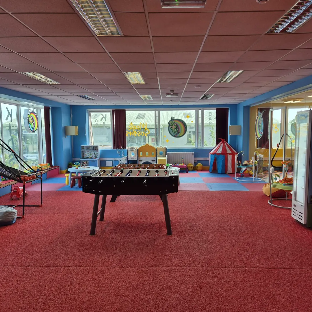 The blue play area with a foosball table, a red and white circus tent, a slide and soft play mats.