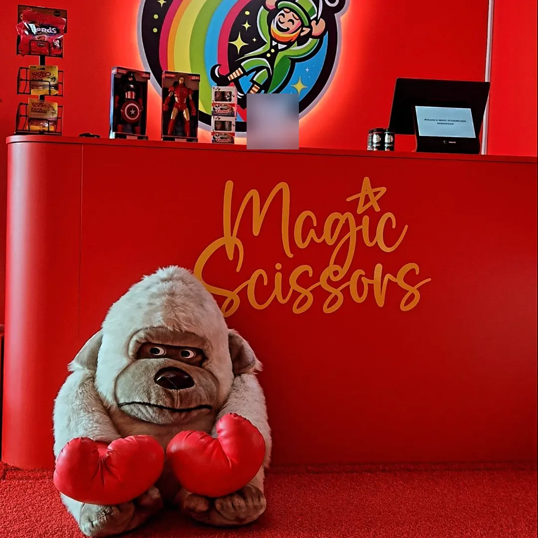 The red reception counter with a gold Magic Scissors sign and a big toy gorilla in boxing gloves.